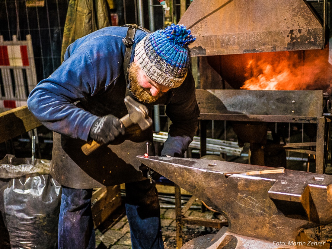 Foto: Martin Zehrer - Mit gezielten Hammerschlägen richtet der Schmied, dessen Name Reiner Windschiegl aus Neuhaus bei Windischeschenbach ist, einen Riegel für einen Kunden, der am Stand warte 